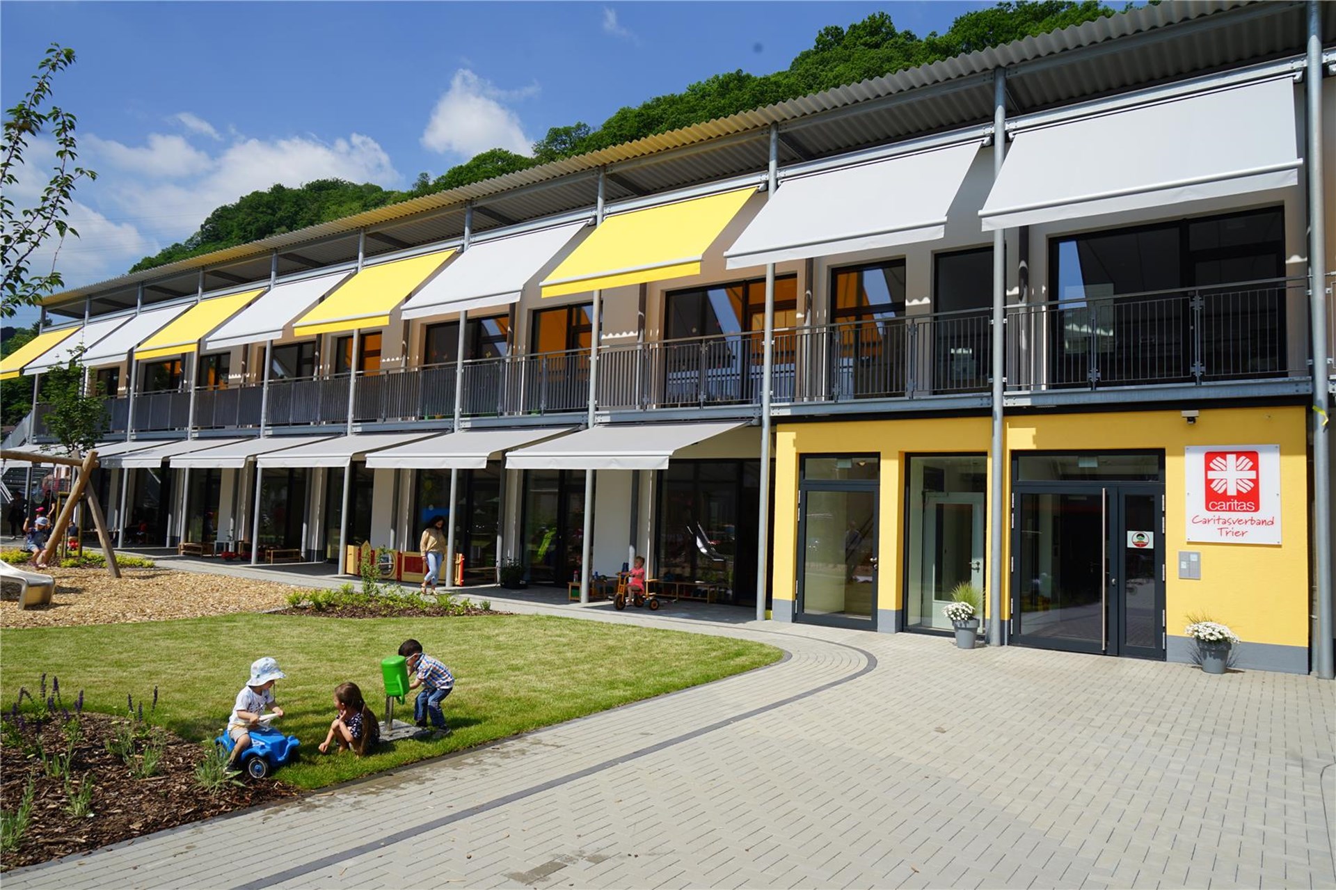 Blick auf ein langes Gebäude mit gelben und hellgrauen Markisen: das neue Walburga-Marx-Haus
