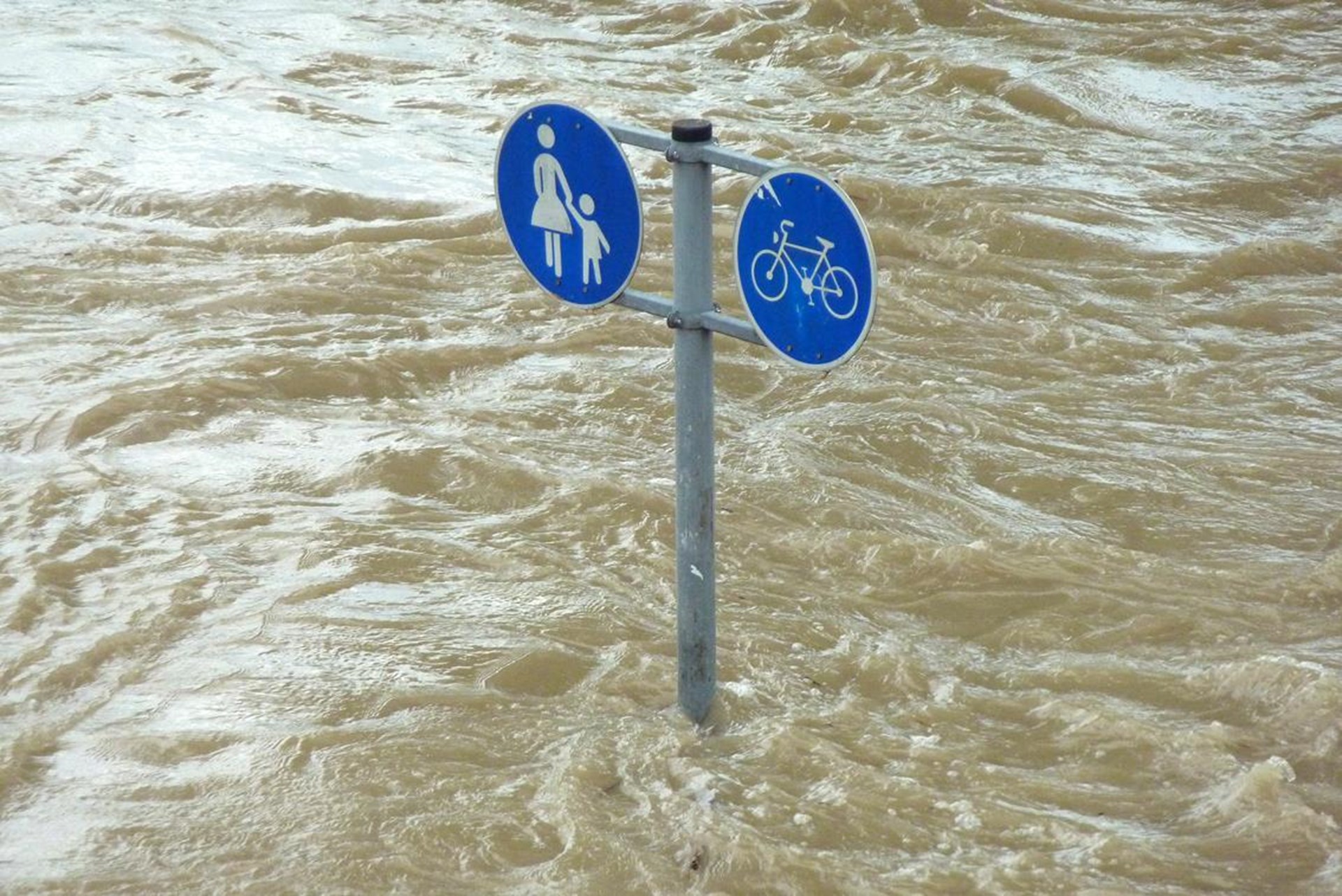 Verkehrsschild ragt aus braunen Wassermassen auf