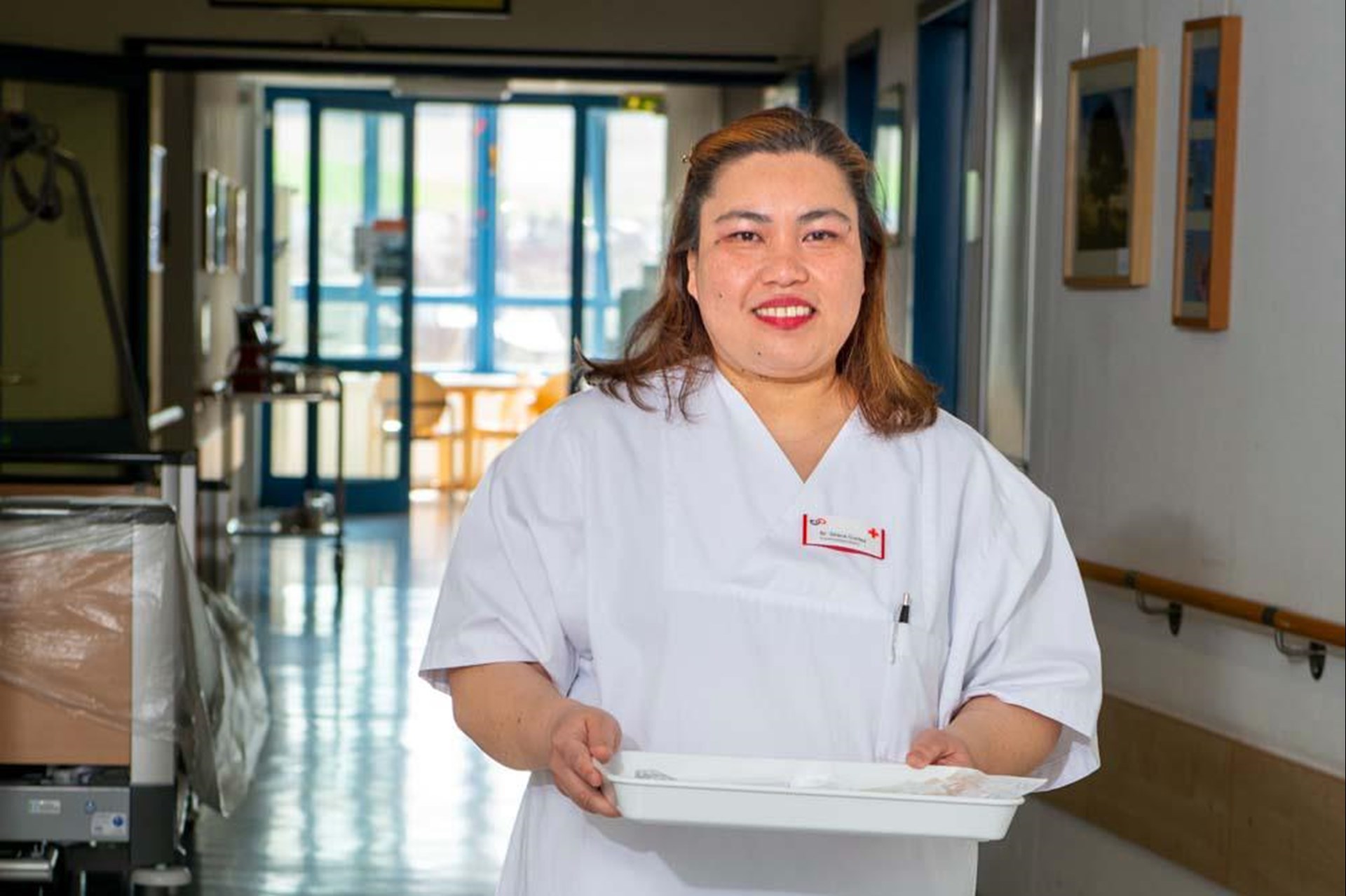 Pflegerin mit Tablett in einem Krankenhausflur